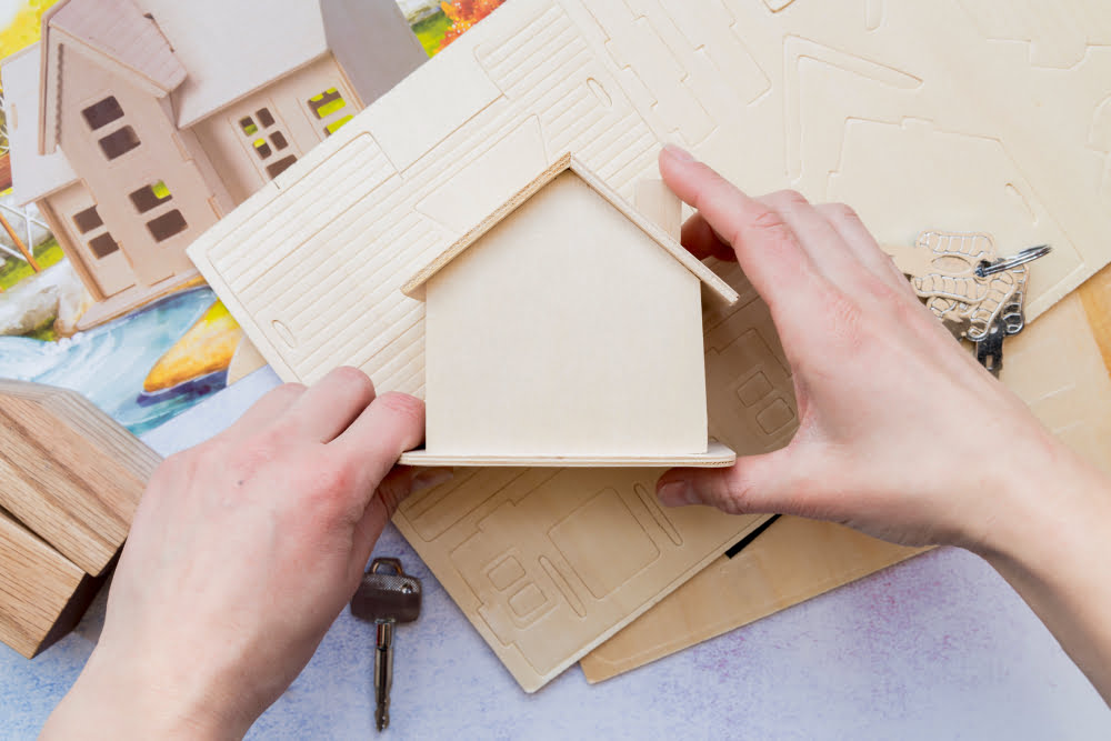 Quais as vantagens de construir uma casa modular 4 close up hand holding wooden miniature house model