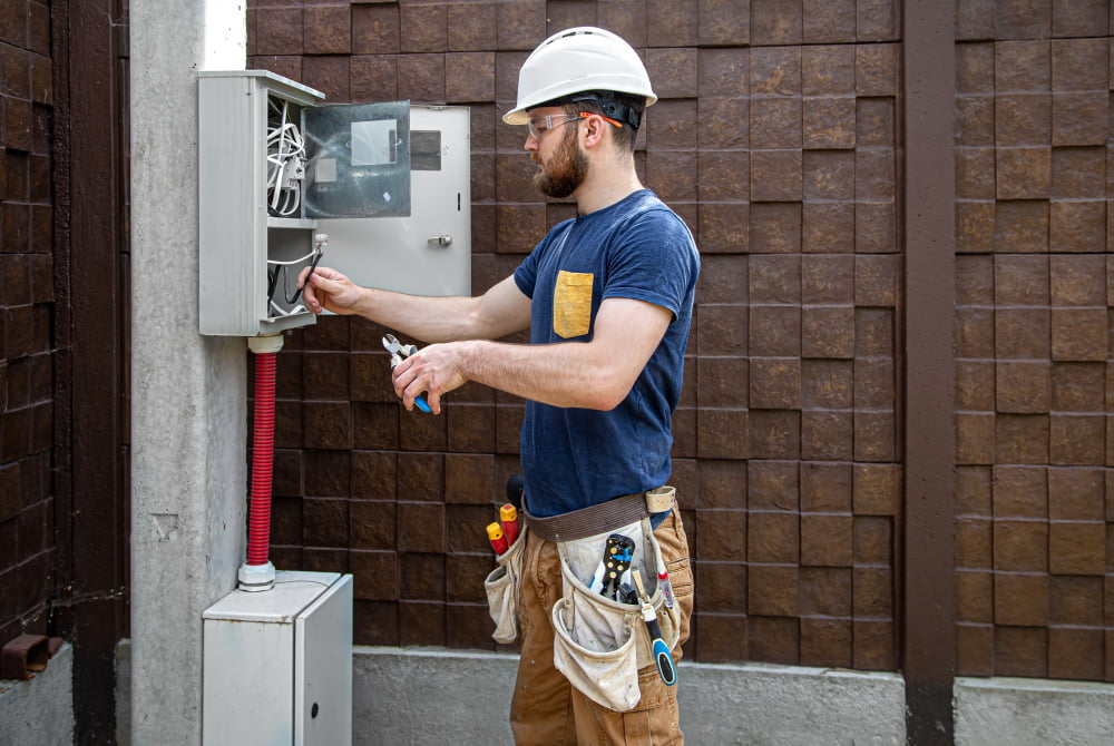 Como funciona a instalação de energia Enel? 4 electrician builder work examines cable connection electrical line fuselage industrial switchboard professional overalls with electrician s tool
