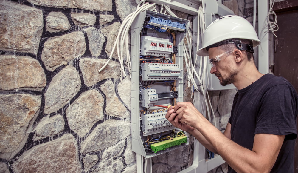 Como funciona a instalação de energia Enel? 2 male electrician works switchboard with electrical connecting cab